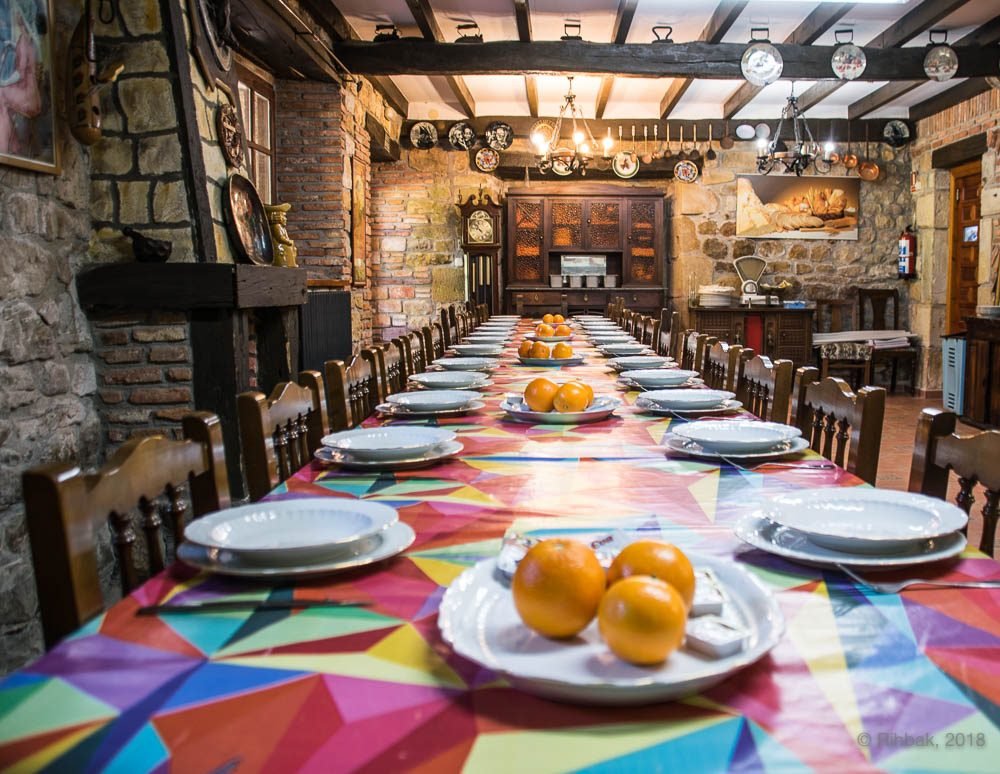 Salón de celebraciones de Finca Gándara con vigas de madera, mesas decoradas y mantelería de colores